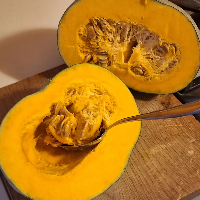 Removing seeds and strings from the pumpkin before cutting it into pieces.