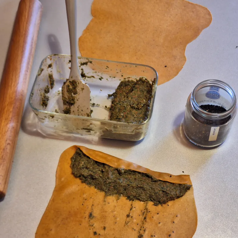 Here we place the filling on the pasta matta rolled out with a rolling pin. I am using white sesame seeds to decorate the outside of the parmesan parcels and black sesame seeds for the sun-dried tomato and paprika parcels
