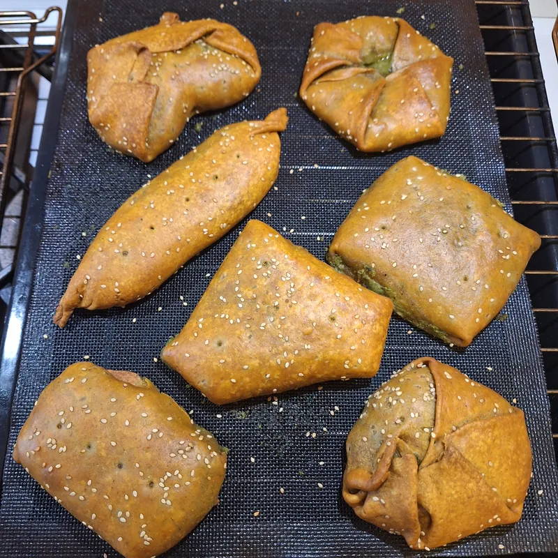 The baked, golden parmesan parcels, with white sesame seeds on the surface